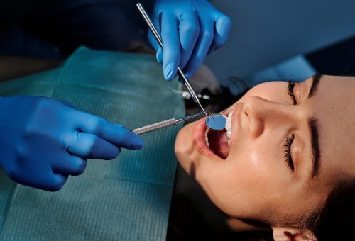 Close-up of a dentist examining a patient's teeth using dental tools.